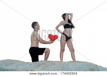 Lovely young adult couple standing on the rocks above tropical sea in isolated.