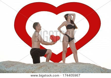 Lovely young adult couple standing on the rocks above tropical sea in isolated.