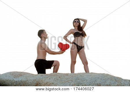 Lovely young adult couple standing on the rocks above tropical sea in isolated.