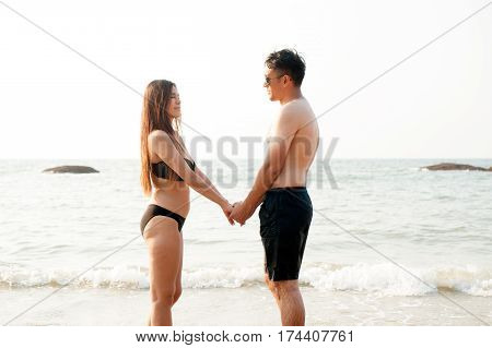 Lovely young adult couple standing on the beach.