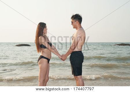 Lovely young adult couple standing on the beach.