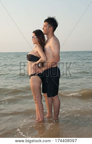 Lovely young adult couple standing on the beach.