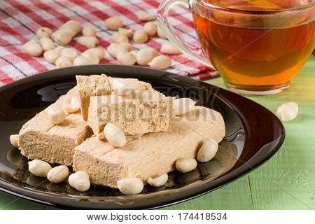 peanut halva in the plate on a green wooden background.