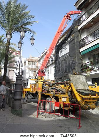 Alora Spain - Febuary 24 2017: Pumping concrete over rooftop into rear of building