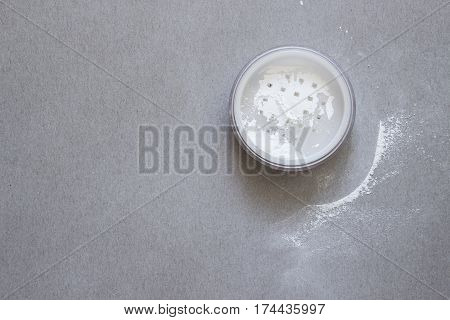 Container with a transparent powder in gray background