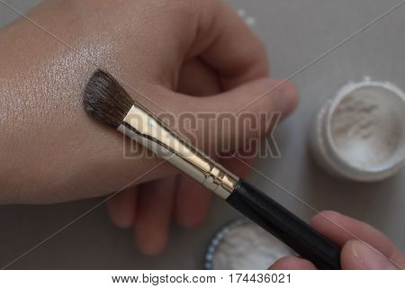 Pearl powder. Female hand applied by brush perly eyeshadow on hand