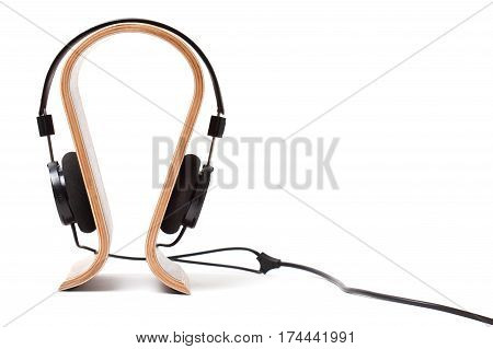Black Pair of Headphones on a wooden stand Isolated on a White Background