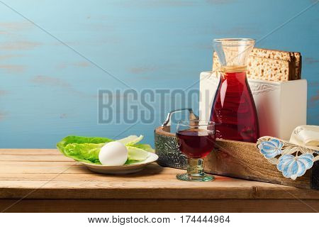 Jewish holiday passover concept with wine matzoh egg and lettuce over wooden background with copy space