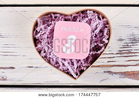 Heart-shaped box on wooden background. Holiday of womanhood.