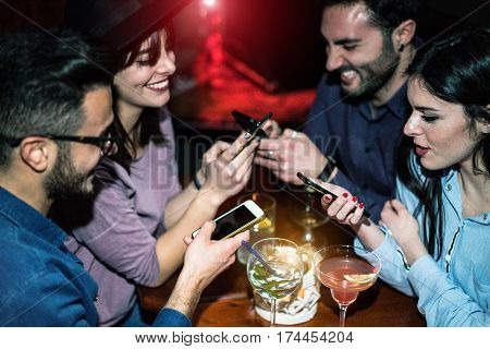 Happy friends using mobile phones in jazz cocktail bar - Young people are addicted to new trends technology - Online social concept - Focus on right girl face - Unfiltered photo made with flash