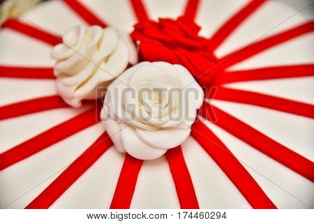 Sweet cakes in the form of red roses decorate the wedding cake with more decorative twigs of white cream. Photographed at a wedding in Novi Sad, Serbia.