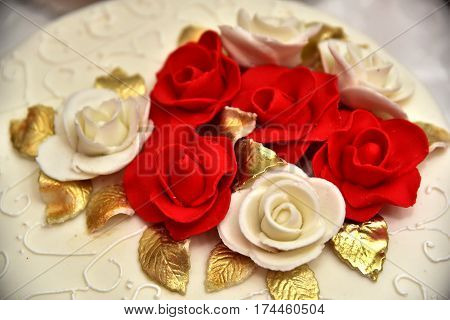 Sweet cakes in the form of red roses decorate the wedding cake with more decorative twigs of white cream. Photographed at a wedding in Novi Sad, Serbia.