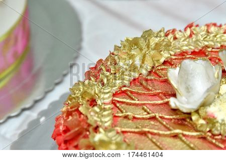 Sweet cakes in the form of red roses decorate the wedding cake with more decorative twigs of white cream. Photographed at a wedding in Novi Sad, Serbia.