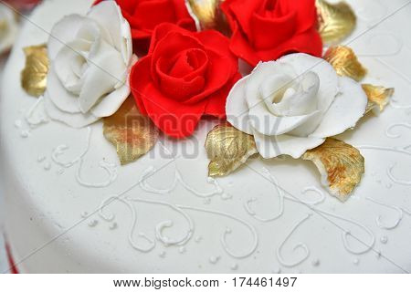 Sweet cakes in the form of red roses decorate the wedding cake with more decorative twigs of white cream. Photographed at a wedding in Novi Sad, Serbia.