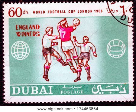 DUBAI - CIRCA 1966: Postage stamp printed in Dubai  with a picture of a football players, with the inscription 
