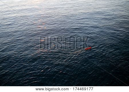 Two women in red kayak rowing in the open waters of Mediterranean Sea, near the coast of Vernazza, Cinque Terre, Italy.