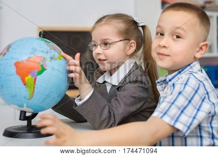 closeup portrait of  schoolchildren are examining globe