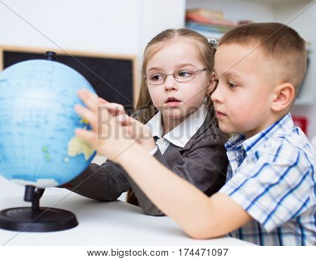 closeup portrait of  schoolchildren are examining globe