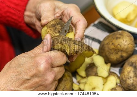 Close-up of hands peeling potato before cooking