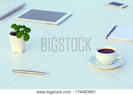 White working Place with Electronic Gadgets Paper Notepad Pen Coffee and green Flower in cold Tones with Copy Space