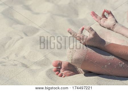 Child making yoga exercises sitting on a warm sand. People and lifestyle concept.