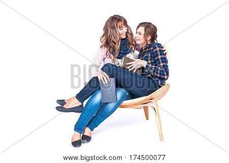 Full length portrait of two siting on chair beautiful weman students holding books isolated on a white background