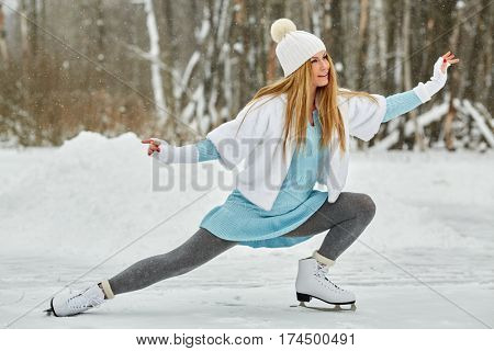 Young woman skates at outdoor skate rink in winter park.