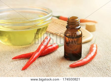 Ingredients for homemade mask stimulating hair growth. Olive oil and red chili pepper tincture, fresh whole plants. Sunshine effect right side.