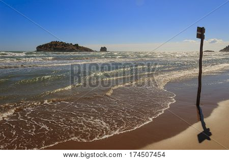 Gargano coast: Portonuovo or Gattarella seascape,Vieste-(Apulia) ITALY-.Sandy beach during a storm: summer wooden signpost on the shore.