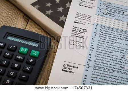 Tax preparation forms and tax tables with calculator on wooden board