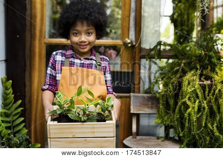 Little Boy Standing Carryin Small Plants in Wooden Tray