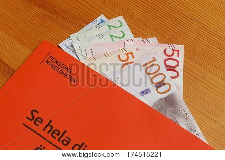 Stockholm Sweden - March 3 2017:The orange envelope from the Swedish Pensions Agency (Pensionsmyndigheten) with teh annual statement on top of Swedish banknotes.