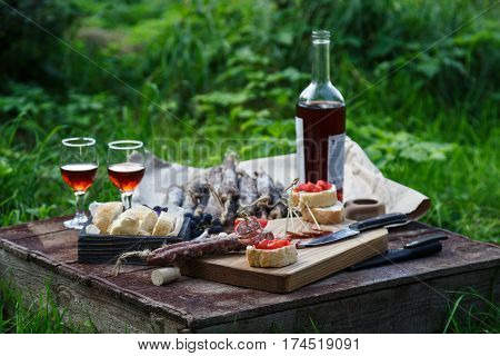 Sausage, tomato, bread and a glasses of red wine, contryside