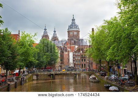 Beautiful cityscape of Amsterdam Canal and St. Nicolas Church at the gloomy rainy summer day. Netherlands. Europe.