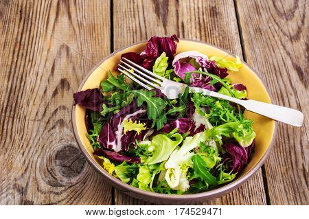 Frise, batavian, radichchio, arugula in a ceramic bowl on a wooden background. Studio Photo