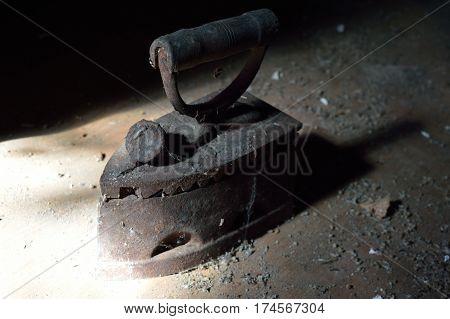 Old cast-iron iron lit by sun on the dark loft
