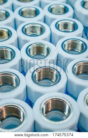 Plumbing connection fittings for plastic pipes. Orderly arranged in neat rows. Abstract industrial background.