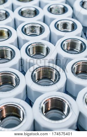 PVC Plumbing connection fittings for plastic pipes. Orderly arranged in neat rows. Abstract industrial background.