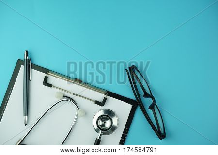 Medical Concept. Top view of stethoscope, clipboard, pen and eye glasses on blue background. Flat lay and copy space.