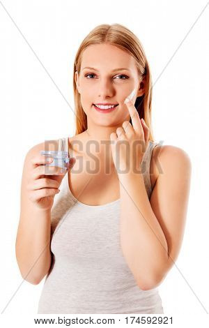 Portrait of young woman applying moisturizer cream on her pretty face