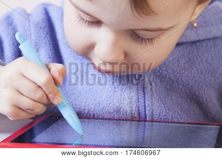 Baby girl drawing on the graphics tablet. The young art and web designer. (Humorous picture)