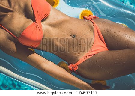 Beautiful woman body on an airbed in the swimming pool