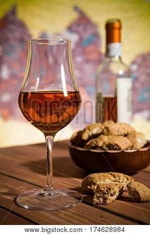 Closeup of a glass of Italian vin santo wine and cantucci biscuits on a wooden table