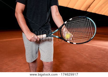 Man in t-shirt with racket on indoor tennis court. Play tennis. Ball in hand