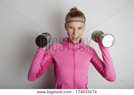 Portrait of fitness young woman wearing pink sports wear. Fresh healthy stylish sport girl posing close to white wall.