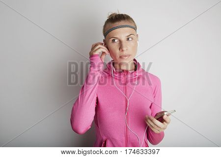 Portrait of fitness young woman wearing pink sports wear. Fresh healthy stylish sport girl listening energetic music.
