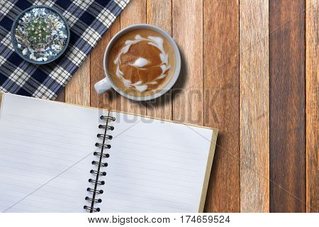 Blank white paper of book and hot coffee on brown desk high angle view