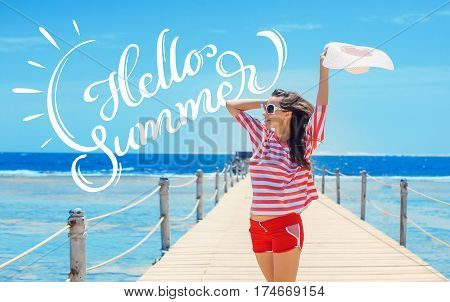 happy woman standing on pier with big white hat and text Hello Summer. Calligraphy lettering.