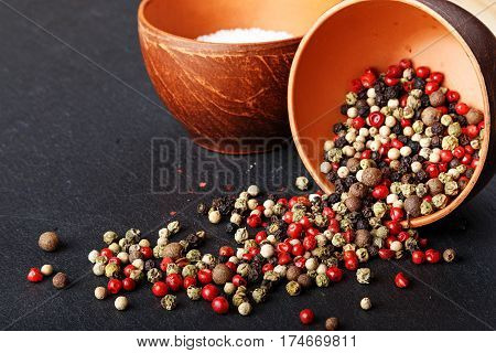 salt and pepper in a clay bowl on a slate board pepper is scattered