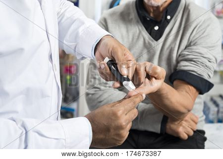 Doctor Checking Sugar Level Of Senior Patient With Glucometer